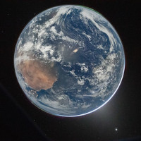 Planet Earth against the blackness of space; a bright point—Venus—is visible at the lower right